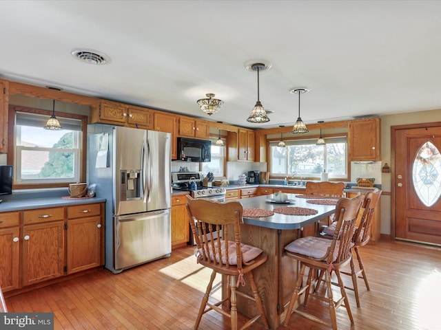 kitchen with pendant lighting, stainless steel appliances, and light wood-type flooring