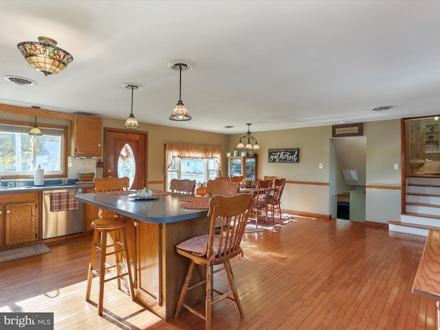 kitchen featuring light hardwood / wood-style flooring, dishwasher, a center island, and a breakfast bar area