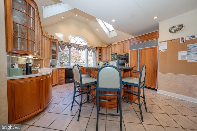 kitchen with light tile patterned floors, black appliances, a kitchen island, and a skylight