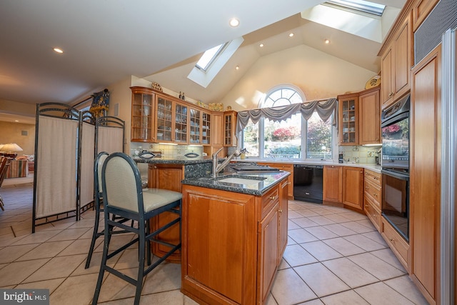 kitchen featuring black appliances, a center island with sink, dark stone counters, and backsplash