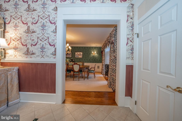 hallway with ornamental molding, light hardwood / wood-style flooring, and a chandelier