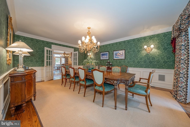 dining area with light hardwood / wood-style floors, an inviting chandelier, and ornamental molding