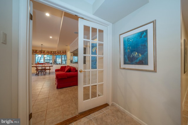 doorway to outside with a notable chandelier and light tile patterned flooring