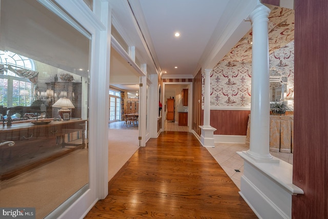 corridor with ornamental molding, hardwood / wood-style flooring, and ornate columns