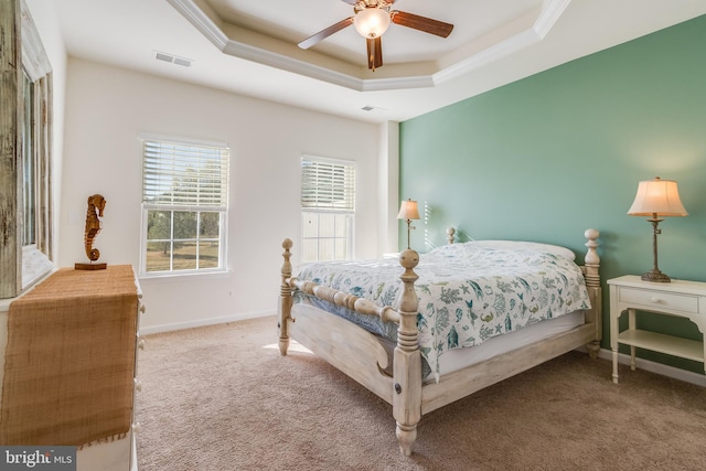 carpeted bedroom with a raised ceiling and ceiling fan