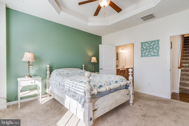 bedroom with connected bathroom, carpet, a raised ceiling, and ceiling fan