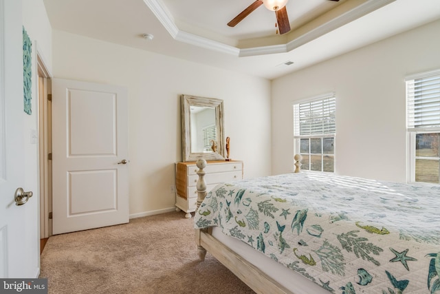 carpeted bedroom with ceiling fan, a raised ceiling, and crown molding