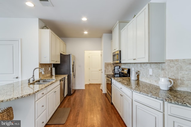 kitchen featuring appliances with stainless steel finishes, hardwood / wood-style floors, sink, and white cabinetry