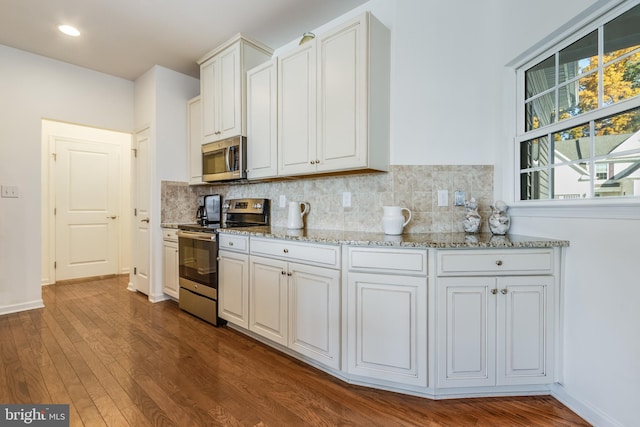 kitchen featuring appliances with stainless steel finishes, dark hardwood / wood-style flooring, white cabinetry, light stone counters, and decorative backsplash