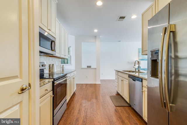 kitchen featuring light stone countertops, appliances with stainless steel finishes, sink, and cream cabinets