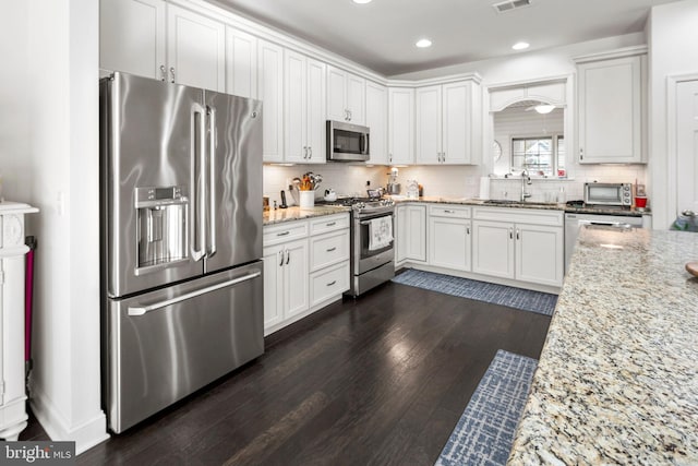 kitchen featuring white cabinetry, light stone countertops, appliances with stainless steel finishes, and sink