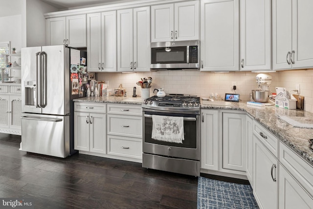 kitchen with dark hardwood / wood-style floors, backsplash, light stone countertops, white cabinets, and appliances with stainless steel finishes