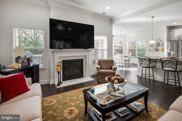 living room featuring ornamental molding, dark wood-type flooring, and a healthy amount of sunlight