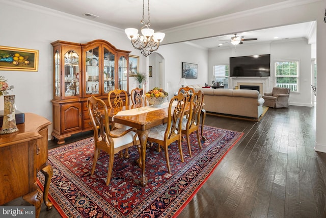 dining area with crown molding, dark hardwood / wood-style floors, and ceiling fan with notable chandelier