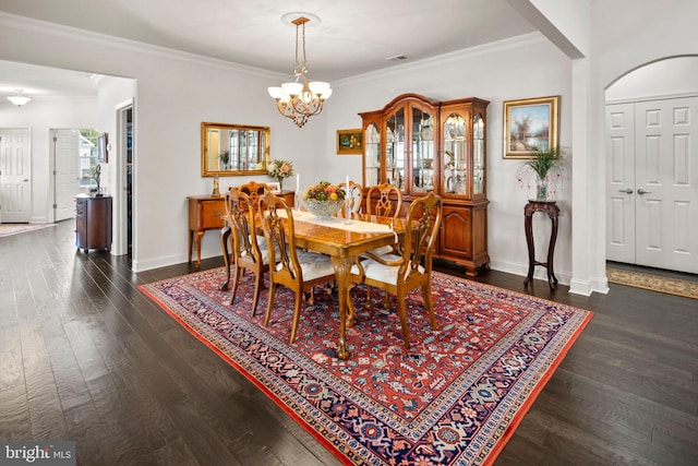 dining space with dark wood-type flooring, a notable chandelier, and crown molding