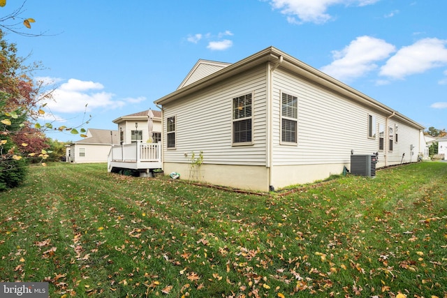 view of home's exterior with cooling unit, a wooden deck, and a lawn