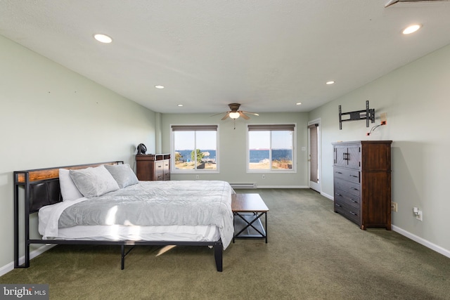 bedroom with dark colored carpet, baseboard heating, and ceiling fan