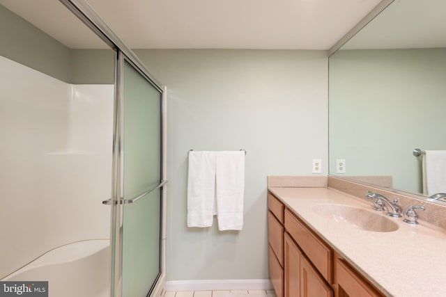 bathroom with a shower with door, tile patterned floors, and vanity