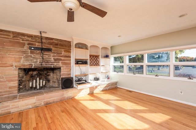 unfurnished living room with a fireplace, wood-type flooring, and ceiling fan