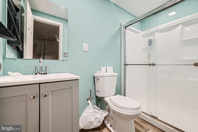 bathroom featuring vanity, toilet, a shower with shower door, and hardwood / wood-style floors