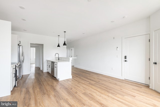 kitchen with appliances with stainless steel finishes, decorative light fixtures, a center island with sink, and white cabinets