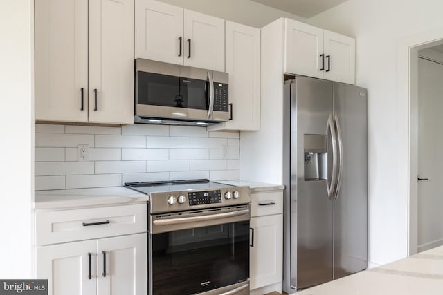 kitchen with white cabinetry, light stone counters, stainless steel appliances, and decorative backsplash