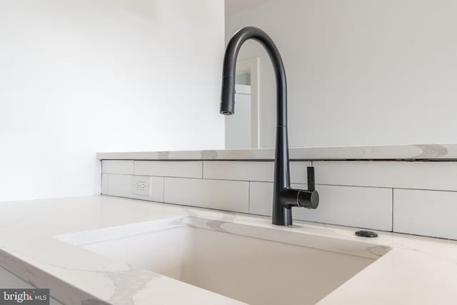 room details with white cabinetry, light stone countertops, and sink