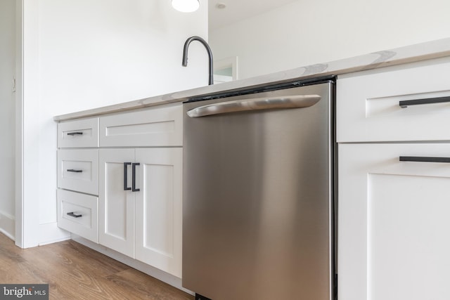 interior details with white cabinetry, stainless steel dishwasher, and light wood-type flooring