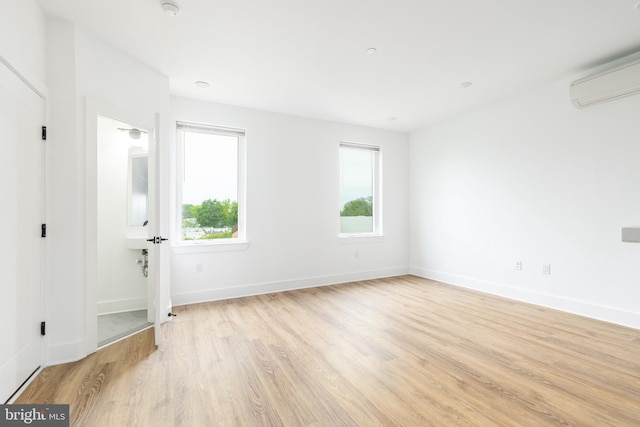 unfurnished room featuring light hardwood / wood-style floors and a wall unit AC