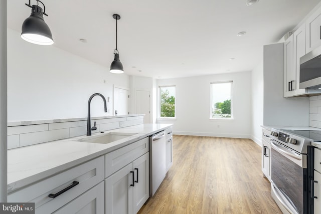 kitchen featuring tasteful backsplash, appliances with stainless steel finishes, sink, white cabinetry, and light stone counters