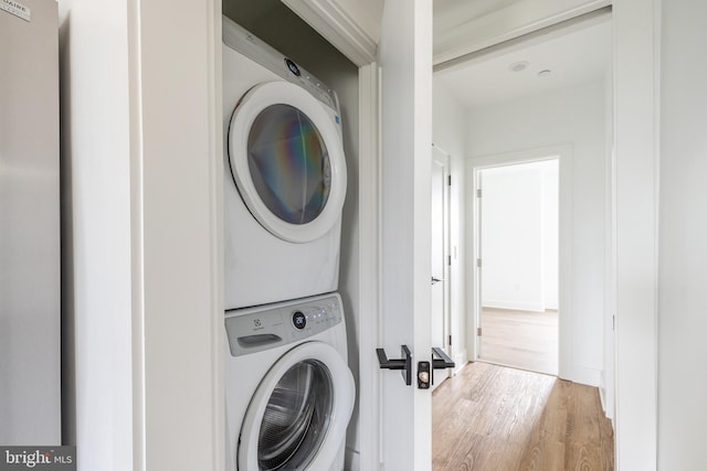 laundry area featuring stacked washer / dryer and wood-type flooring