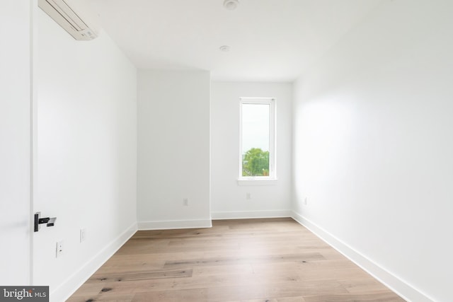 empty room featuring light hardwood / wood-style floors and an AC wall unit