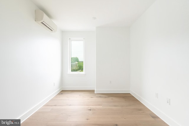 spare room with a wall mounted air conditioner and light hardwood / wood-style floors