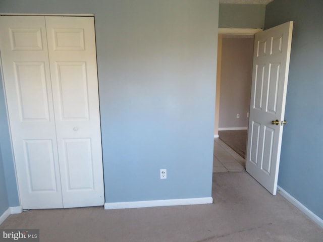 unfurnished bedroom featuring light colored carpet and a closet