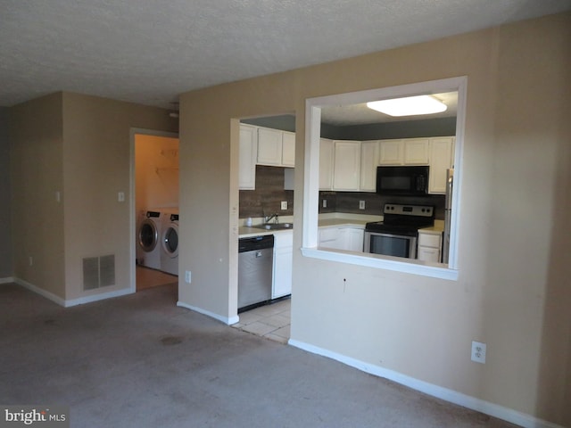 kitchen featuring white cabinetry, stainless steel appliances, and washer and clothes dryer