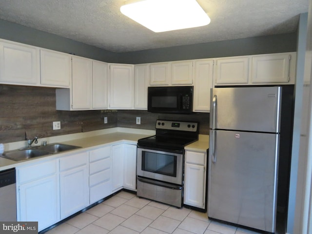 kitchen featuring decorative backsplash, appliances with stainless steel finishes, white cabinetry, a textured ceiling, and sink