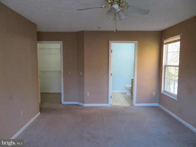 spare room with a textured ceiling, light colored carpet, and ceiling fan