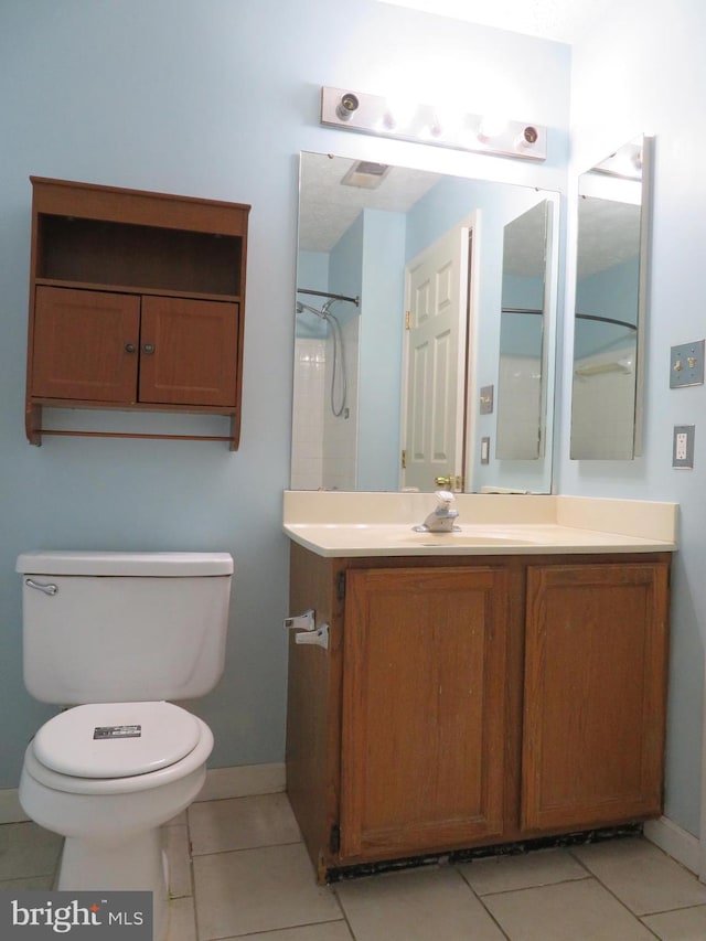 bathroom with toilet, a shower, vanity, and tile patterned floors