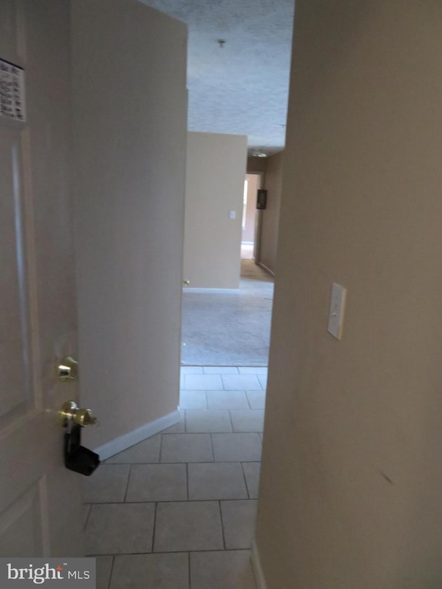 hallway featuring light tile patterned flooring and a textured ceiling