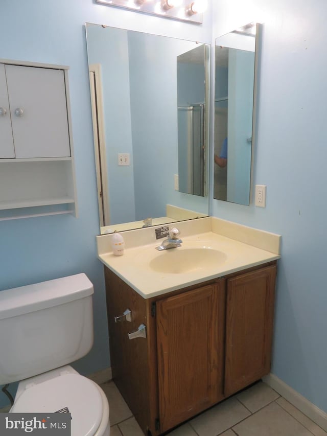 bathroom featuring vanity, toilet, walk in shower, and tile patterned flooring