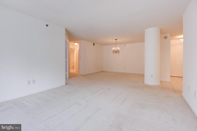 empty room with light colored carpet and an inviting chandelier