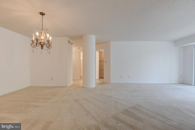 carpeted spare room with a notable chandelier and a textured ceiling