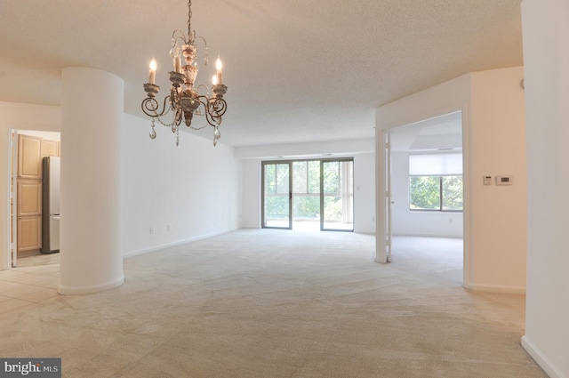 carpeted empty room with a textured ceiling and an inviting chandelier