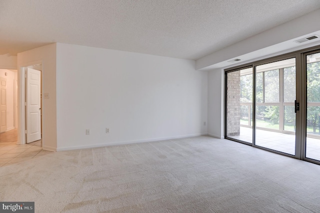 spare room featuring light carpet and a textured ceiling