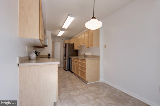 kitchen with stainless steel fridge, hanging light fixtures, stove, light brown cabinetry, and sink