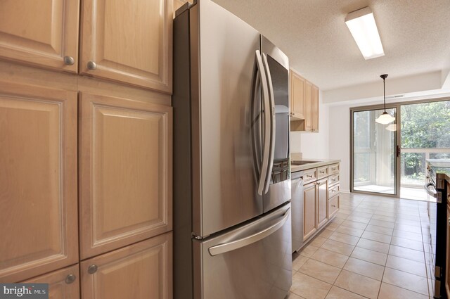 kitchen featuring light brown cabinets, a textured ceiling, light tile patterned flooring, stainless steel appliances, and decorative light fixtures