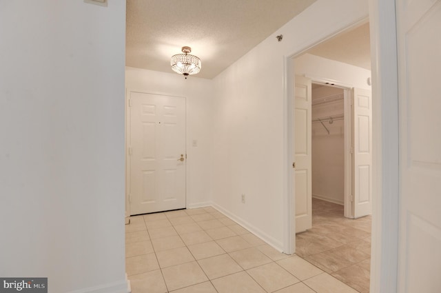 tiled entryway with a textured ceiling and an inviting chandelier