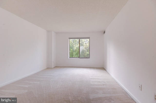 unfurnished room featuring a textured ceiling and light colored carpet