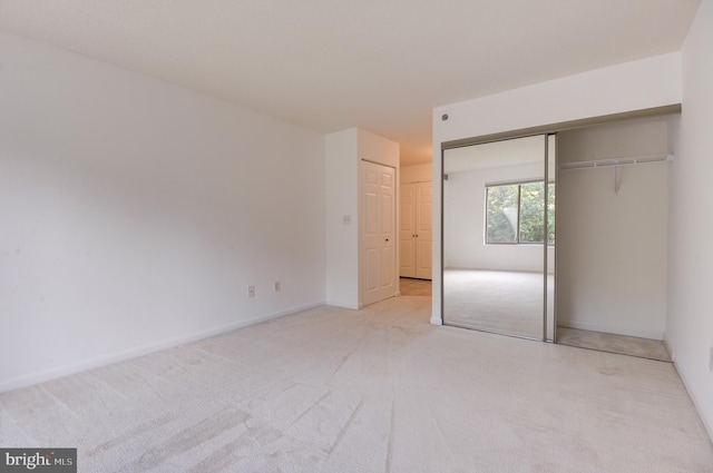 unfurnished bedroom with a closet and light carpet