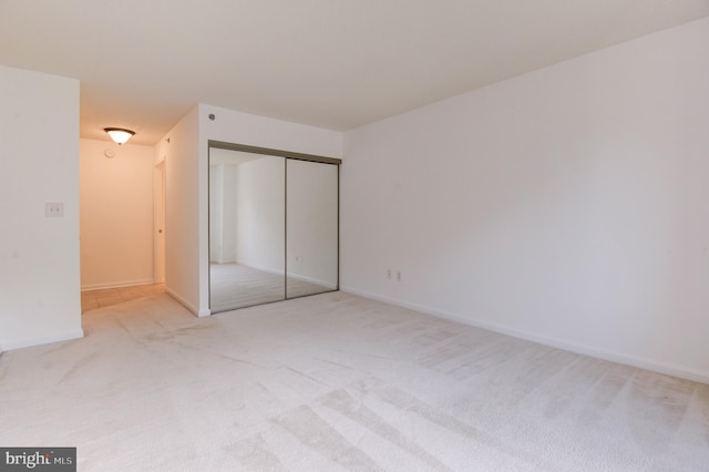 unfurnished bedroom featuring a closet and light colored carpet